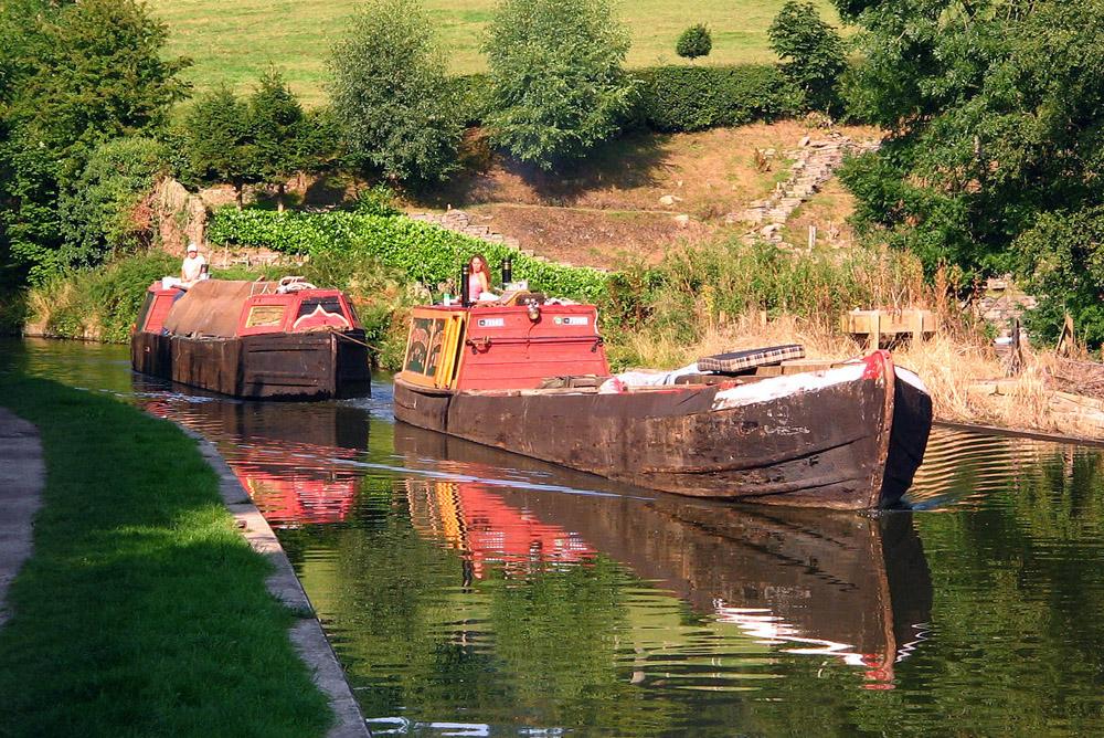 Historic working narrow boats on the Macclesfield Canal in Cheshire, England. The leading boat, Forget Me Not is hauling the un-powered butty Lilith. This became a familiar operating pattern once motors began to replace horses. (Source: Wikipedia. Image is Public Domain)
